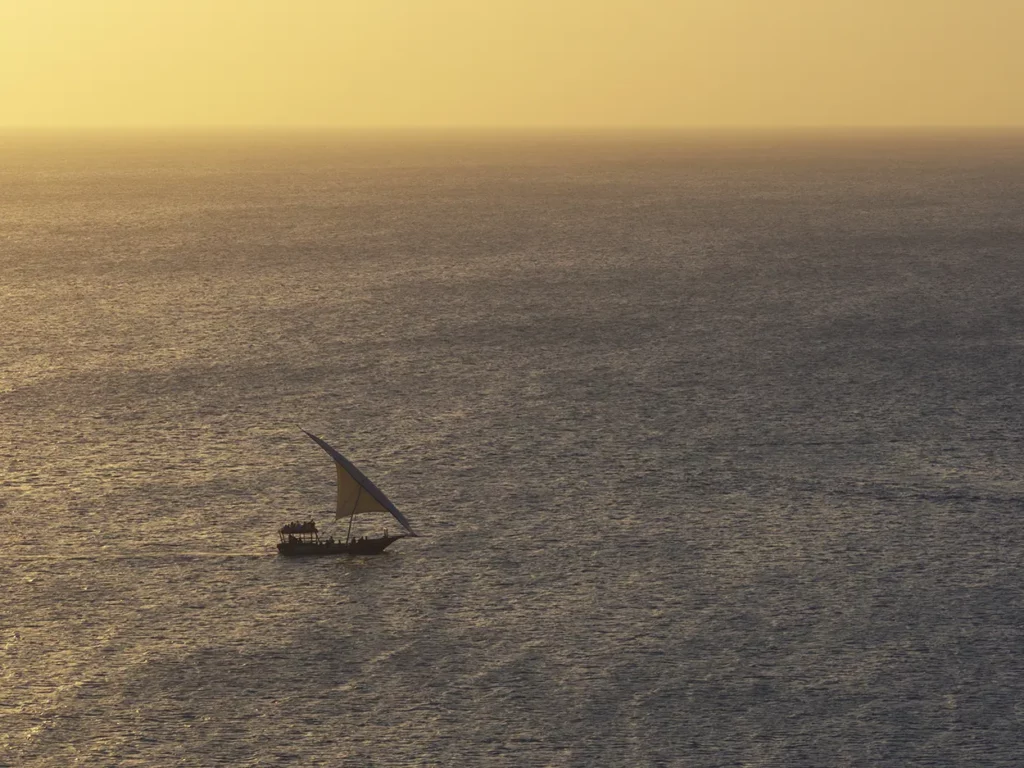 Am aerial image of a dhow on the sea at sunset in Zanzibar