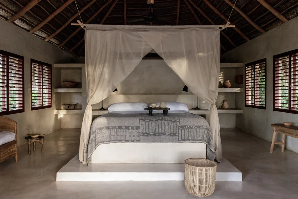 Beach lodge main bedroom with high thatch ceilings and neutral details.