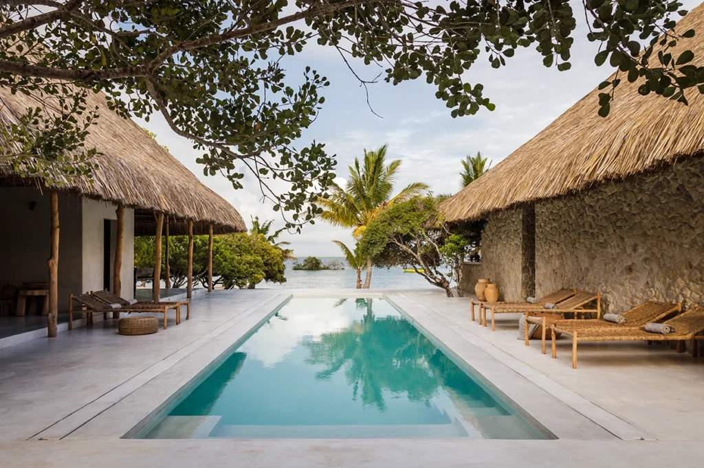 Wide-angle shot of Sussurro Mozambique lodge swimming pool with lagoon view.